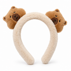 Fluffy cream headband with two plush capybara heads on a white background