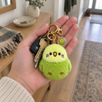Adult hand holding keys with the green budgie plush keychain