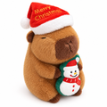 Capybara plush in a gold-embroidered Merry Christmas Santa hat hugging a little snowman on a white background