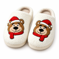 Cream fuzzy slippers with an embroidered brown bear in a Santa hat on a white background