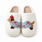 Cream fuzzy slippers with an embroidered dachshund in a blue sweater on a white background