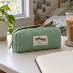Mint green corduroy shark pencil case on a desk with a notebook and pencils