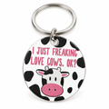 Round cow-print keychain with a cartoon cow face on a silver ring, on a white background