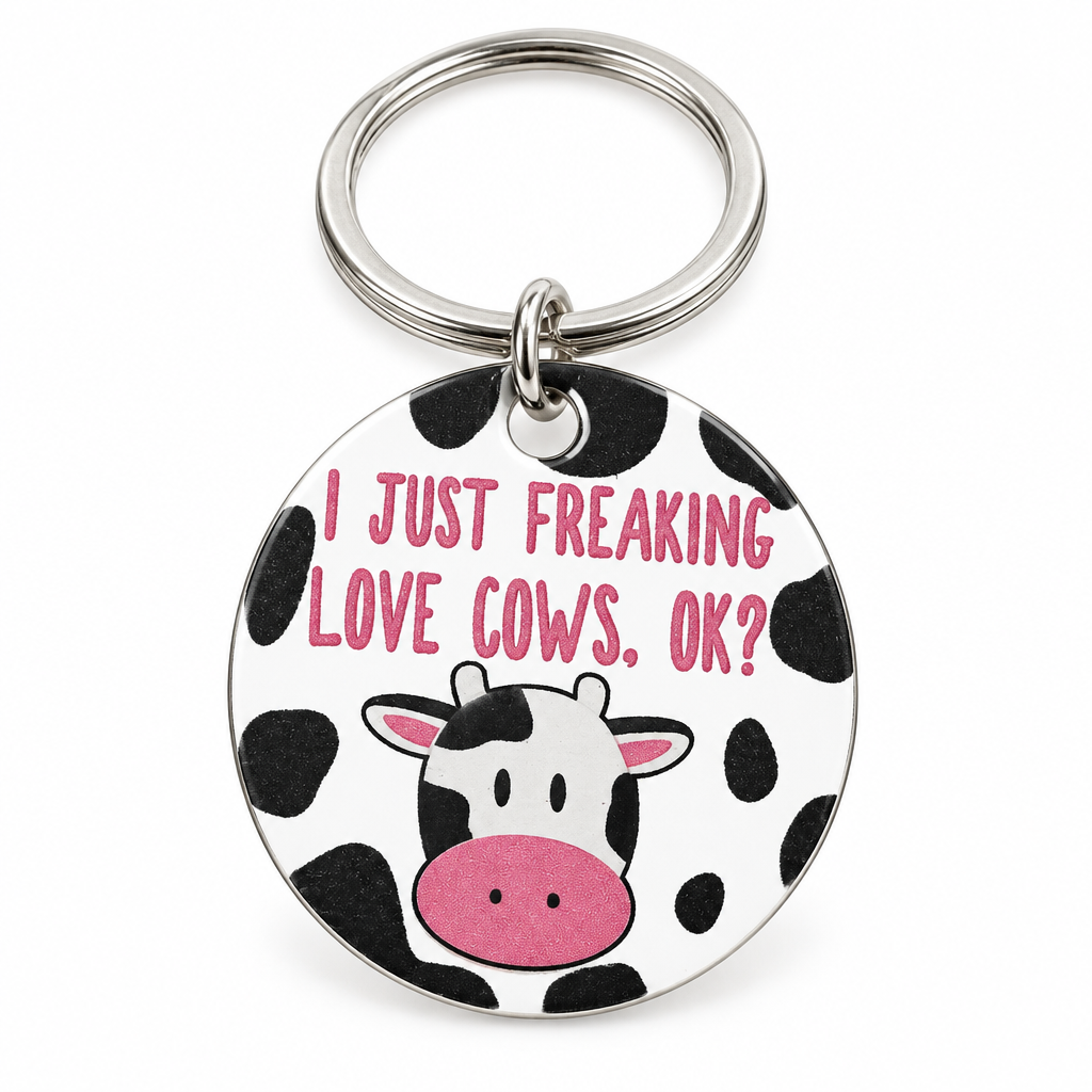 Round cow-print keychain with a cartoon cow face on a silver ring, on a white background