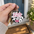 Cow-print keychain hanging from house keys in an adult hand by a front door