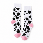Pair of white cow print crew socks with pink heels and toes on a white background