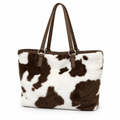 White plush tote bag with chocolate-brown cow spots and brown straps on a white background