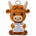 Crochet highland cow keychain holding a "Positive Moo" message card on a white background
