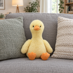 Fluffy yellow duck plush sitting on a gray sofa