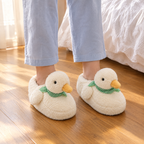 White Fluffy Duck Slippers worn on a wooden bedroom floor beside the bed in morning light