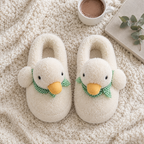 White Fluffy Duck Slippers flat lay on a knit blanket with cocoa, a book and greenery
