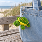 Green sea turtle keychain hanging from a denim tote bag zipper