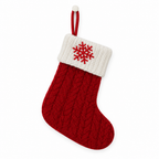Red knit Christmas stocking with an embroidered snowflake on the cuff on a white background