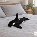 Black and white orca plush lying on a made bed