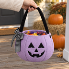 Lilac pumpkin bucket bag full of candy held by an adult hand on a porch