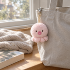 Pink octopus keychain hanging from a canvas tote bag zipper