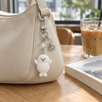 Seal pup bag charm clipped to a cream leather shoulder bag