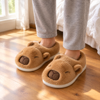 Brown Sleepy Capybara Slippers worn on a wooden bedroom floor beside the bed