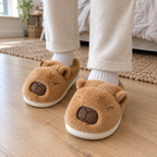 Adult feet wearing brown capybara plush slippers on a wooden bedroom floor