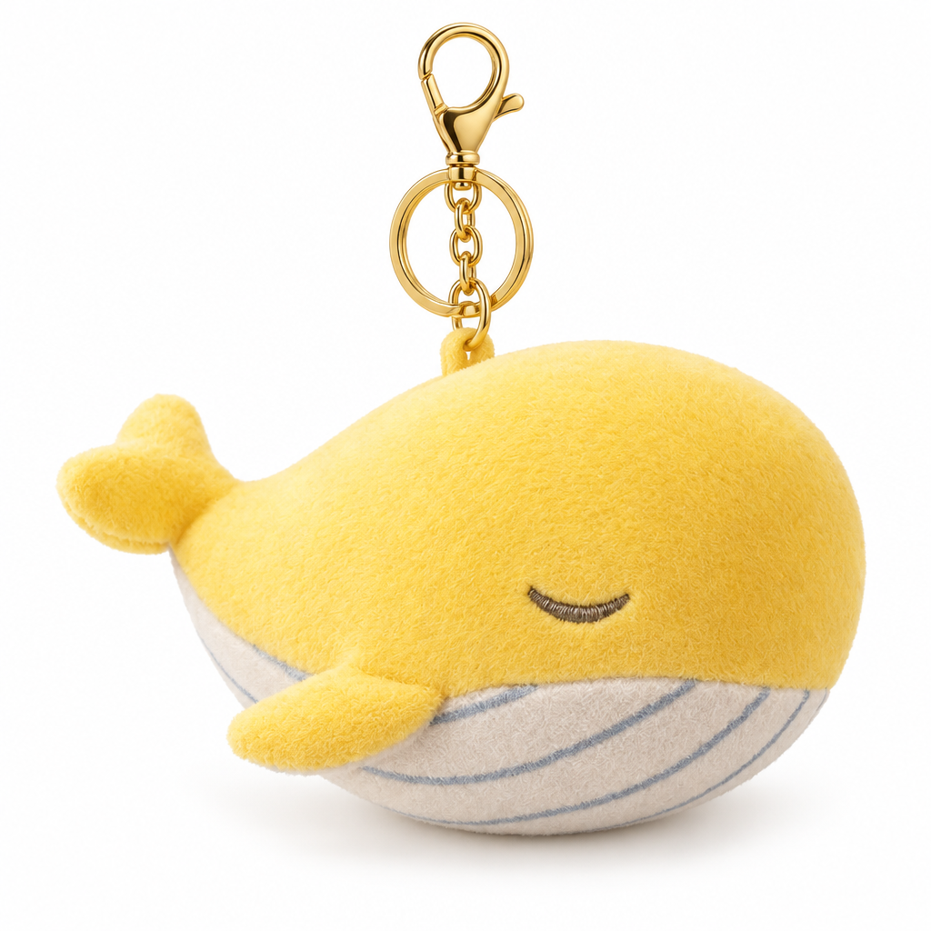 Yellow whale plush keychain with a gold-tone clasp on a white background