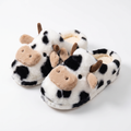 White plush slippers with black cow spots and 3D cow faces on a white background