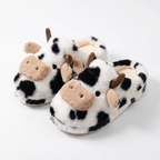 White plush slippers with black cow spots and 3D cow faces on a white background