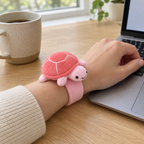 Pink plush turtle slap bracelet worn on an adult wrist at a desk