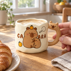 Wavy capybara mug of latte on a breakfast table with an adult hand on the handle