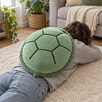 Adult lying on a living room rug wearing the sage green turtle shell pillow on their back