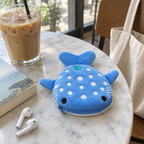 Blue whale shark coin purse on a cafe table next to an iced coffee