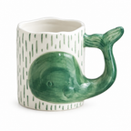 White ceramic mug with a green 3D whale and whale tail handle on a white background