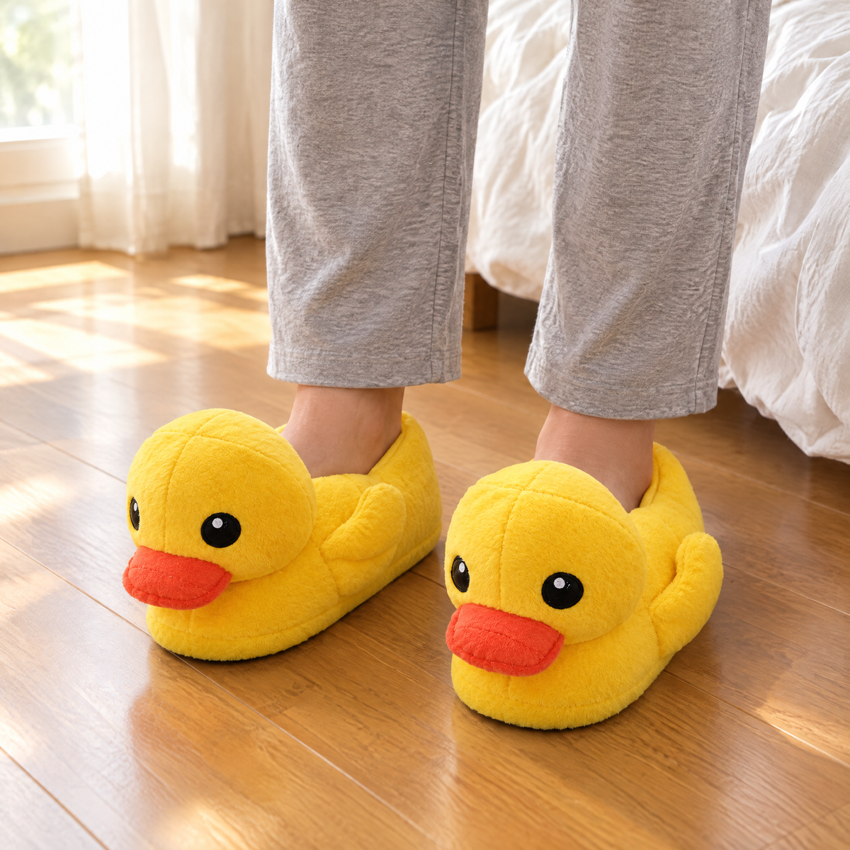 Yellow Duck Plush Slippers worn on a wooden bedroom floor beside the bed in morning light